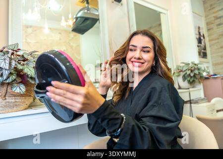 Woman admiring new hairstyle in salon mirror Stock Photo
