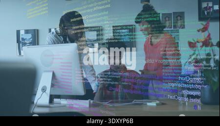 Reviewing three adults in collared shirt, dark tops holding phone checking code on office monitor Stock Photo