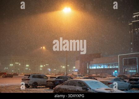 Heavy winter snowfall and blizzard in city, parking lot with cars near supermarket covered in snow. Stock Photo