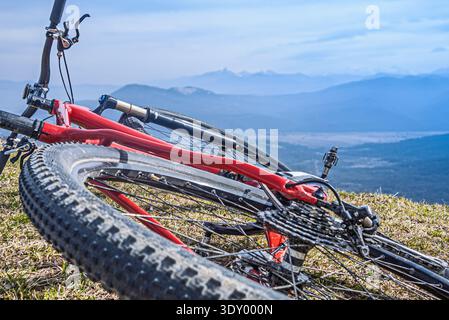 Mountain bike lying on grass with scenic mountain view Stock Photo