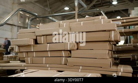 Stacks of packed furniture in cardboard boxes ready for shipping in a large industrial warehouse Stock Photo
