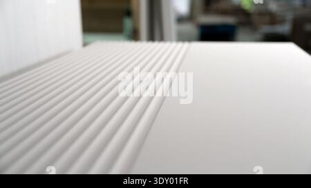 Modern white fluted furniture panel with ribbed texture, close-up view in a workshop. Stock Photo