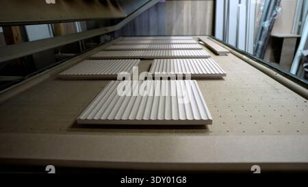 CNC machine milling fluted wood panels. Furniture production and modern woodworking in a carpentry workshop. Stock Photo