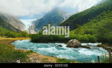 Wide lens shot: Briksdal glacier with a mountain river in the foreground. The amazing nature of Norway Stock Photo