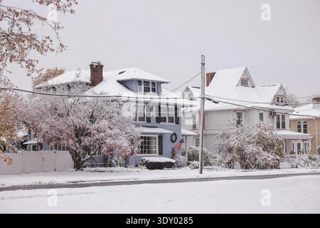 Snow-covered American suburban houses with frosted trees and winter decorations along a quiet residential street after fresh snowfall. Stock Photo