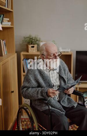 Senior Caucasian Man with Disability Reading Document at Home Stock Photo