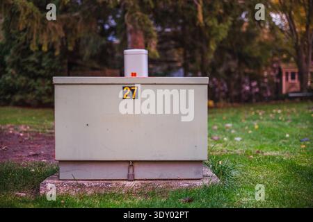 Power distribution box on a green lawn in a suburban area at dusk Stock Photo