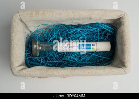 Pre-filled Mounjaro tirzepatide injection pen in a fabric tray with blue shredded paper on a white background, healthcare concept. Stock Photo