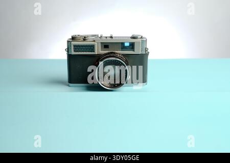 Vintage rangefinder film camera centered on pastel blue surface with white background, minimal studio lighting, retro photography concept with copy sp Stock Photo