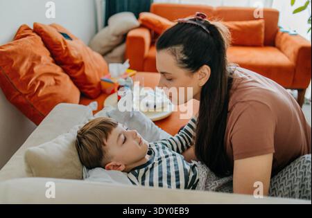 Loving mother comforting her sick son feeling poorly at home Stock Photo
