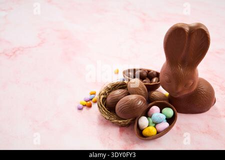 Chocolate bunny, easter eggs, and candy treats on pink Stock Photo