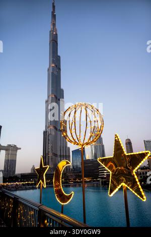 A vertical low-angle photograph capturing illuminated gold decorations in the shape of a crescent moon, stars, and a sphere against the backdrop of th Stock Photo