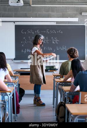 Female teacher explaining science formula to students in classroom Stock Photo