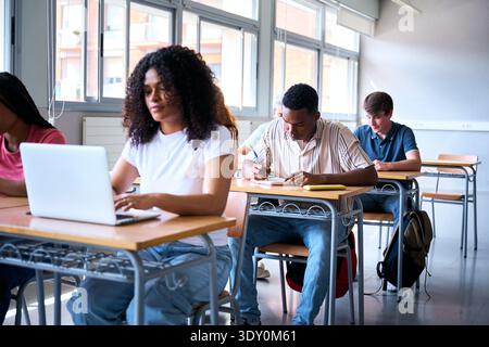Focused students using laptop and writing in classroom Stock Photo