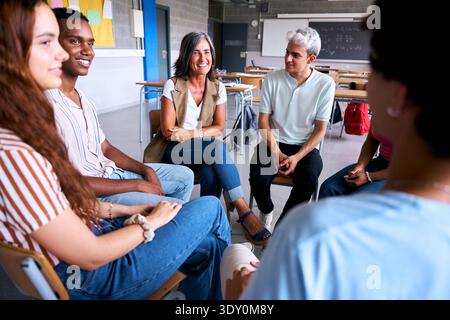 Smiling teacher and students sitting in circle for discussion Stock Photo