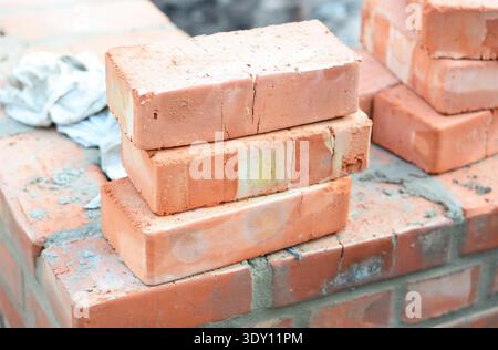 stack of red clay bricks on construction site close up Stock Photo