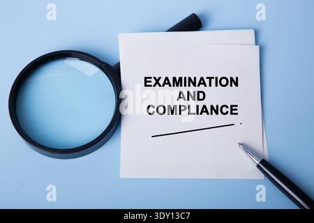 Inspecting examination and compliance documents with a magnifying glass and pen on a blue background Stock Photo