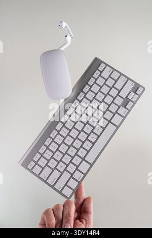 Balancing a Keyboard Mouse and Earbuds on a White Background Stock Photo