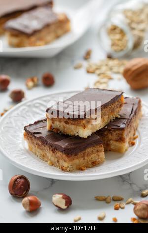 Homemade Vegan cocoa dates chocolate bars with coconut, hazelnuts, walnuts and sunflower seeds on a white background. Healthy dessert. The concept of Stock Photo