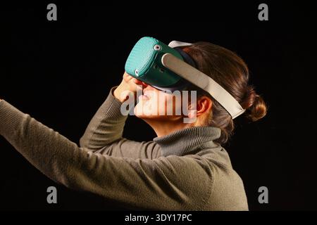Woman exploring virtual reality with an expressive gesture, capturing excitement, discovery and the immersive atmosphere of modern digital technology Stock Photo