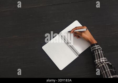 Black woman writing in notebook, top view Stock Photo