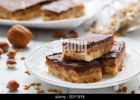 Homemade Vegan cocoa dates chocolate bars with coconut, hazelnuts, walnuts and sunflower seeds on a white background. Healthy dessert. The concept of Stock Photo