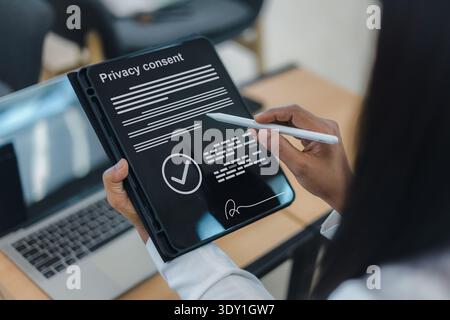 Close up of a businesswoman using a stylus pen to sign a digital privacy consent form on a tablet screen, ensuring data protection and legal complianc Stock Photo