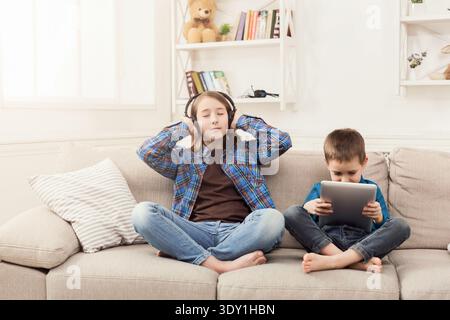 Two kids listening music on couch at home Stock Photo