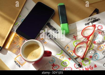 Calendar with business appointments and deadlines,pens,coffee cup smartphone and paperwork on messy workplace. Business concept beat the clock Stock Photo