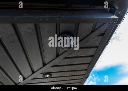 Dome security camera installing under a building roof providing property surveillance Stock Photo