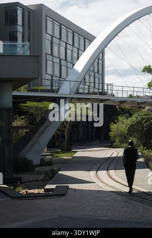 A security guard patrolling on a path under the bridge at the Cape Town Marriott Hotel Crystal Towers located in Century City, Cape Town,South Africa. Stock Photo