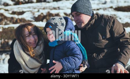 Smiling parents spending time with their son on a winter day, enjoying the snowy landscape Stock Photo
