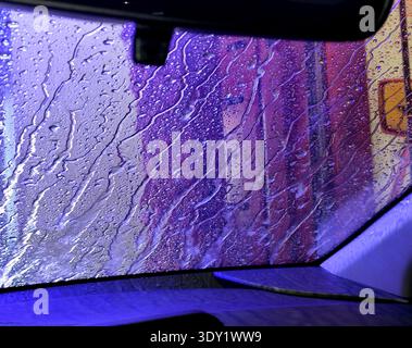 The automatic car wash applies a protective wax at the end of the wash. From inside the car interior, a view out the window of wax dripping down. Stock Photo