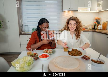 Diverse friends preparing food and using phone in kitchen Stock Photo