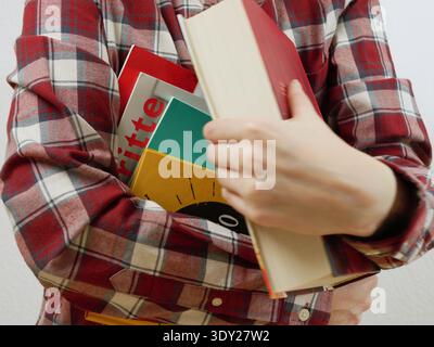 Confident Female Student in Plaid Shirt Holding Stack of Colorful Books and Textbooks Ready for University Class Lecture or Exam Preparation Stock Photo
