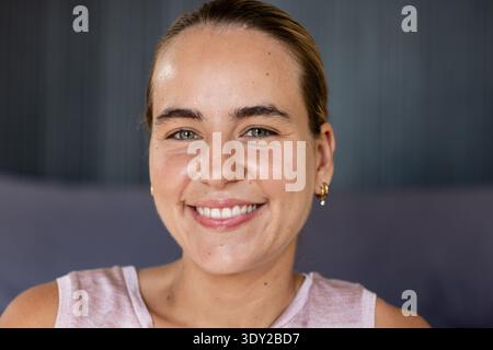 Female posing facing camera in studio with sleeveless pink top and pearl hoop earrings. Portrait, headshot, closeup, skin, texture, lighting, warmth Stock Photo