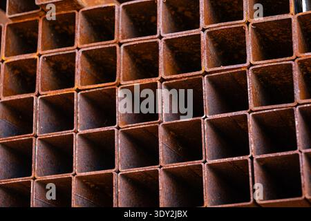 Rusty square metal pipes forming a grid pattern for industrial construction background Stock Photo