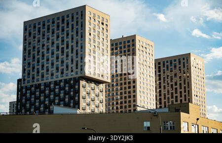 Modern residential buildings rising under blue sky with fluffy white clouds Stock Photo