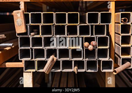 Stacked square steel pipes or metal profiles in a warehouse for industrial construction Stock Photo