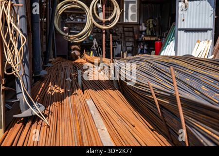 Rusty rebar and metal rods piled, showing construction materials at a metal workshop Stock Photo