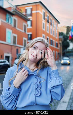 Smiling young woman standing on a European street with colorful buildings. Urban lifestyle and travel concept. Stock Photo