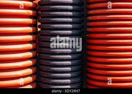 Corrugated orange and black pipes forming a ribbed industrial texture background Stock Photo