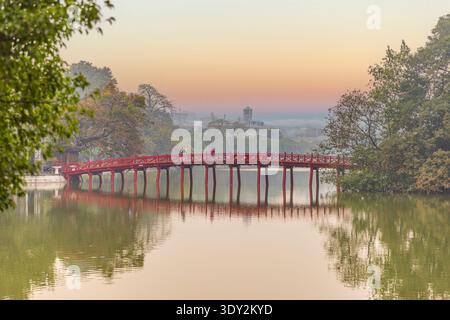The Huc Bridge glows red in the fading light of an orange sunset over Hoan Kiem Lake in Hanoi. Stock Photo