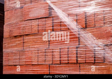 Building materials: new red bricks stacked on a pallet, wrapped in clear plastic Stock Photo