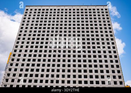 Urban development constructing large building with grid pattern windows under blue sky Stock Photo