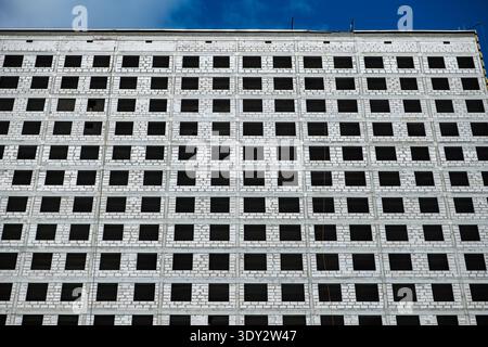 Building facade featuring hundreds of square window openings on a white brick wall Stock Photo