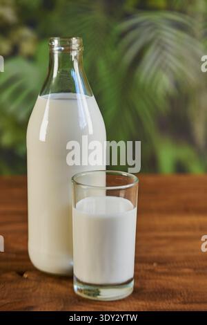 Fresh milk in a glass bottle and drinking glass on a rustic wooden table Stock Photo