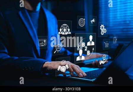 B2B business marketing strategy concept showing a businessman working on a laptop with digital icons of networking, global connection, Stock Photo