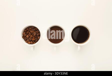 Roasted whole and ground coffee beans in cups, top view, white i Stock Photo