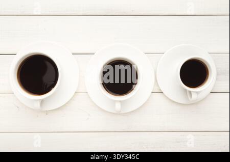 Various cups with black coffee on white wooden table Stock Photo